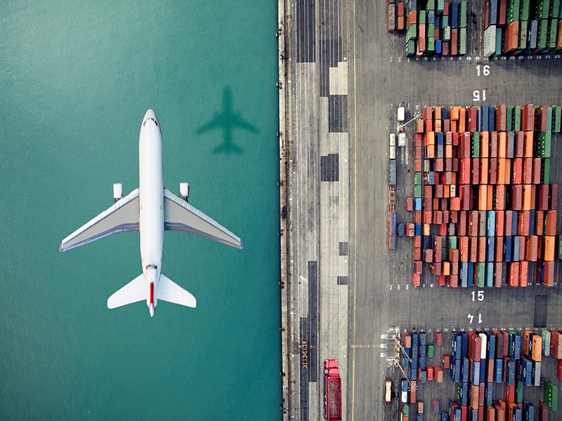 airplane flying over shipping containers