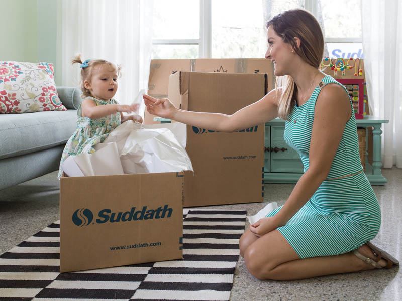 mother packing moving box for international move with female toddler